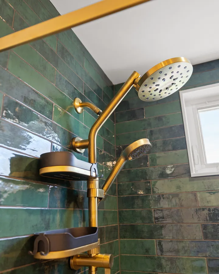 After: glossy green tile, a brass shower column and a window set high in the shower